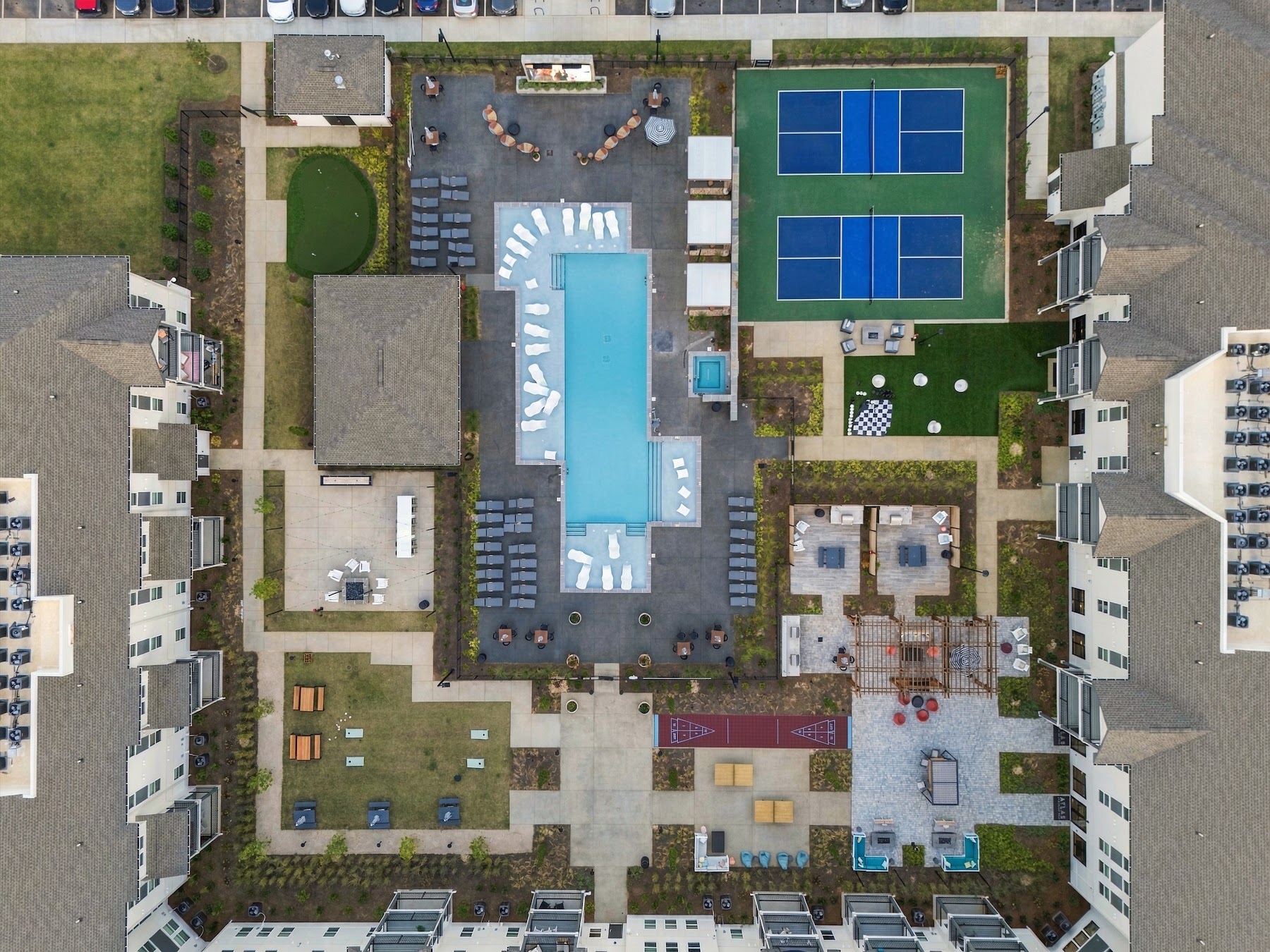 Overhead drone aerial of a commercial apartment amenity center with pool and courts