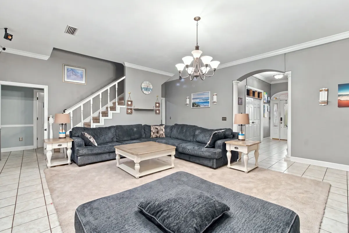 Bright, tidy living room with a sectional sofa and chandelier, photographed for a listing by Tyler Bowman Photography